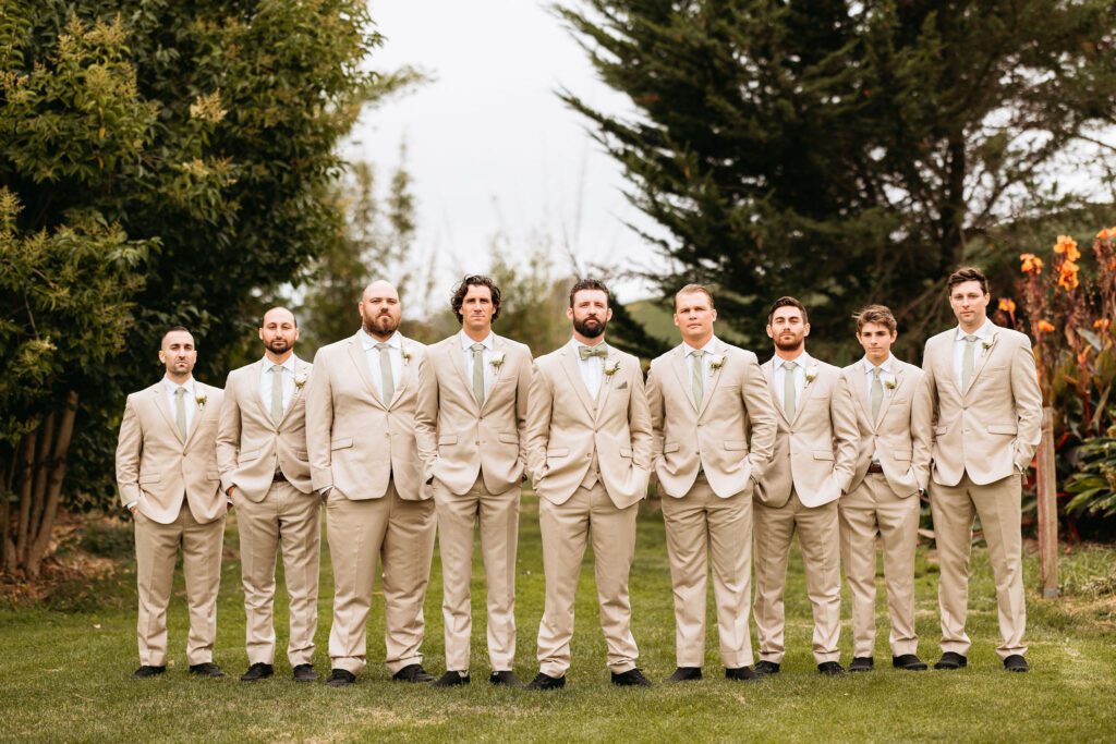 men's beige color suits. outdoor wedding ceremony. The photo shows groom and groomsmen wearing beige or sand suits with green ties.